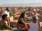 Turismo no Marrocos: viajantes negros em terraço com paisagem inspirada em Marrakech